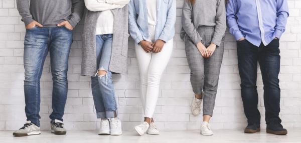Photo of people standing in a line against a white brick wall curious about flexibility in their workplace