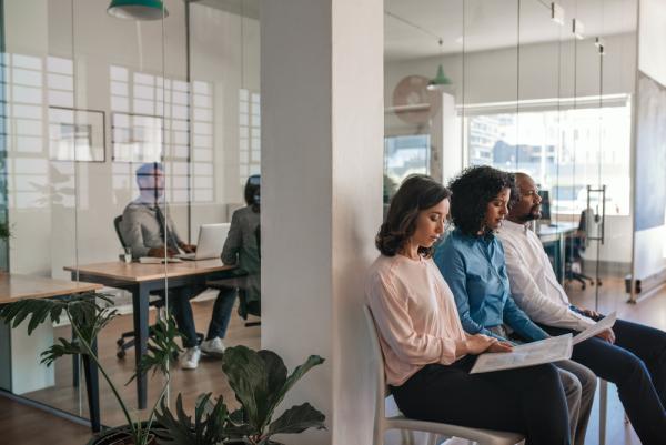 Photo of a person being interviewed in an office of one of the best companies to work for. The picture also includes diverse people waiting outside of the office.