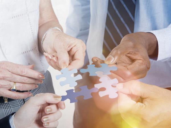 Photo of people’s hands with a blue jigsaw puzzles in their hands
