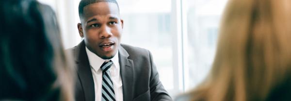 A university administrator holds a discussion with two colleagues, whom we see from behind.