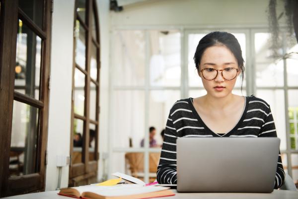 A young woman sits in an airy cafe studying online
