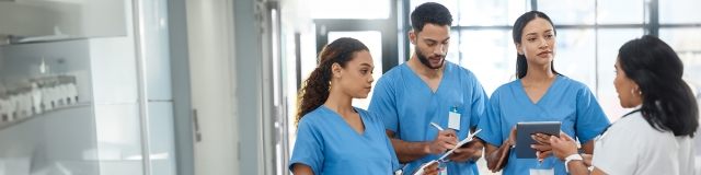 A group of new nurse graduates listens intently as they acclimate to their new roles.